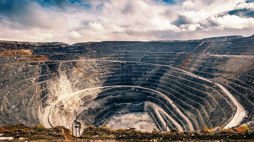 Wide-angle view of Polyus Gold open-pit mine in Russia with terraced levels and cloudy sky Wallpaper
