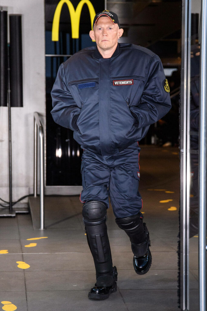 Model in oversized Vetements jacket and pants at Fashion Week inside McDonalds fast food backdrop Wallpaper