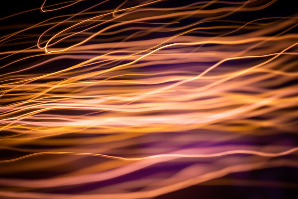 Abstract Light Trails Wallpaper: Vibrant Warm Hues on Dark Background