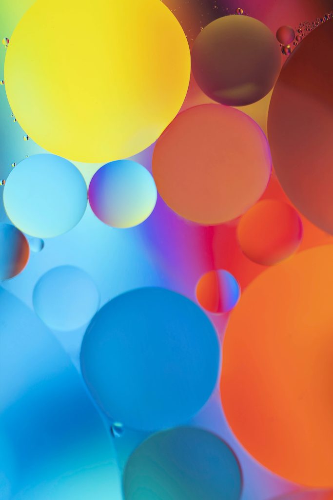 Macro photo of vibrant oil and water bubbles in yellow blue and orange abstract art background Wallpaper