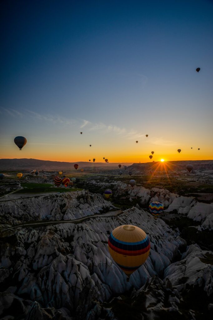 Aerial view of colorful hot air balloons over rugged mountains at sunrise golden light landscape Wallpaper