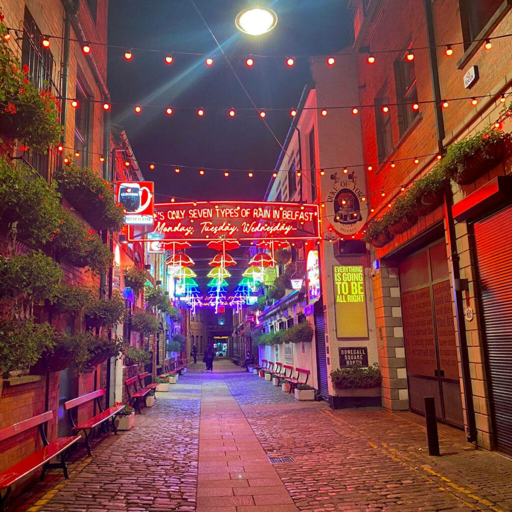 Vibrant Nighttime Alleyway Wallpaper with Neon Lights & Greenery