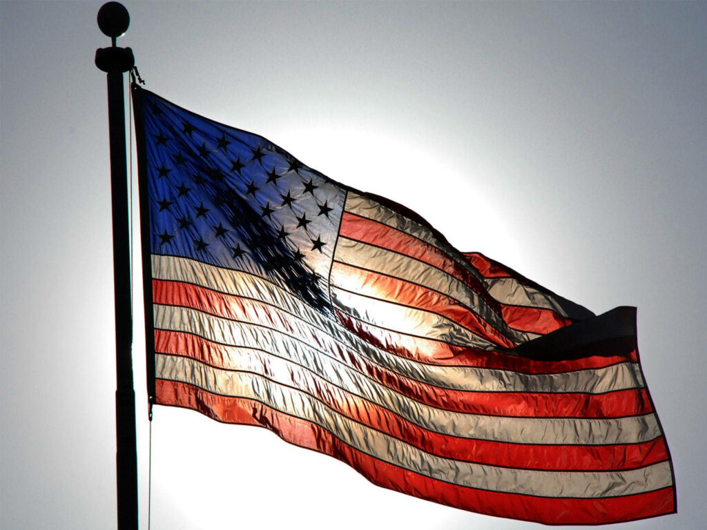 American flag waving brightly against sunlit sky symbolizing freedom and national pride wallpaper