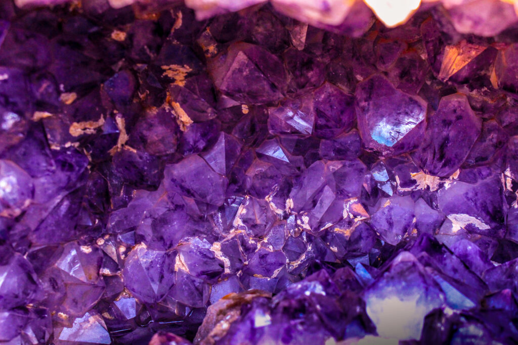 Close-up of vibrant purple amethyst geode crystals with intricate textures and shimmering highlights Wallpaper