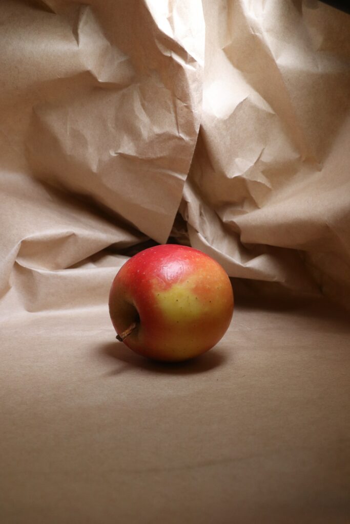 Vibrant Apple on Crumpled Beige Paper – Fresh Natural Wallpaper
