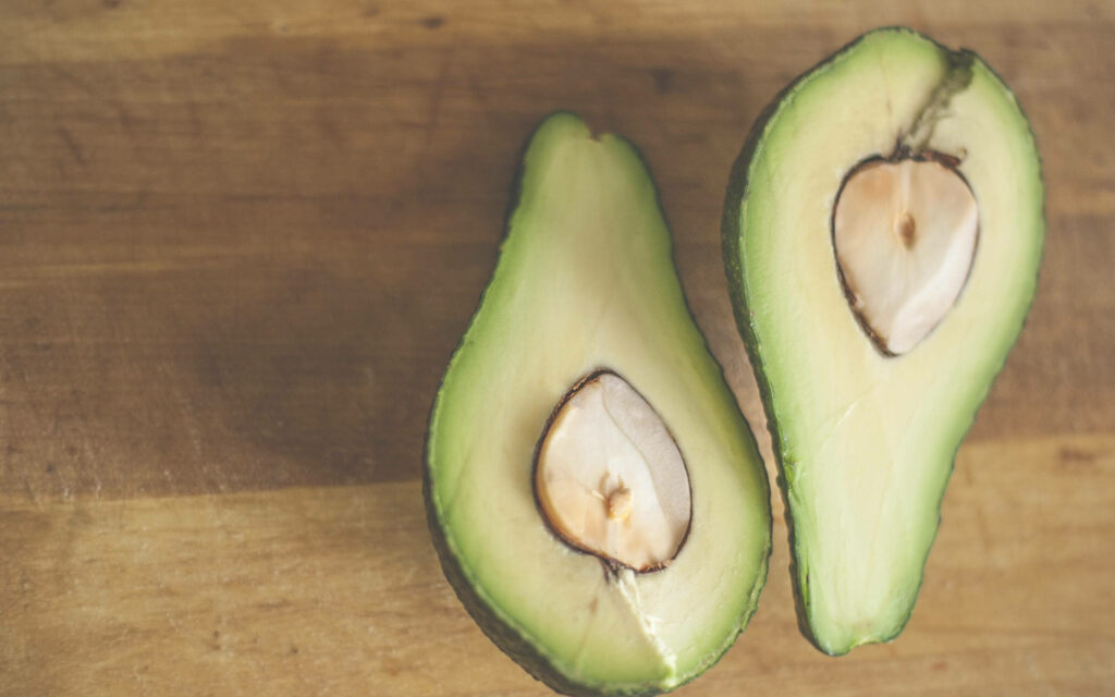 Fresh Avocado Wallpaper: Creamy Halves on Rustic Wooden Background