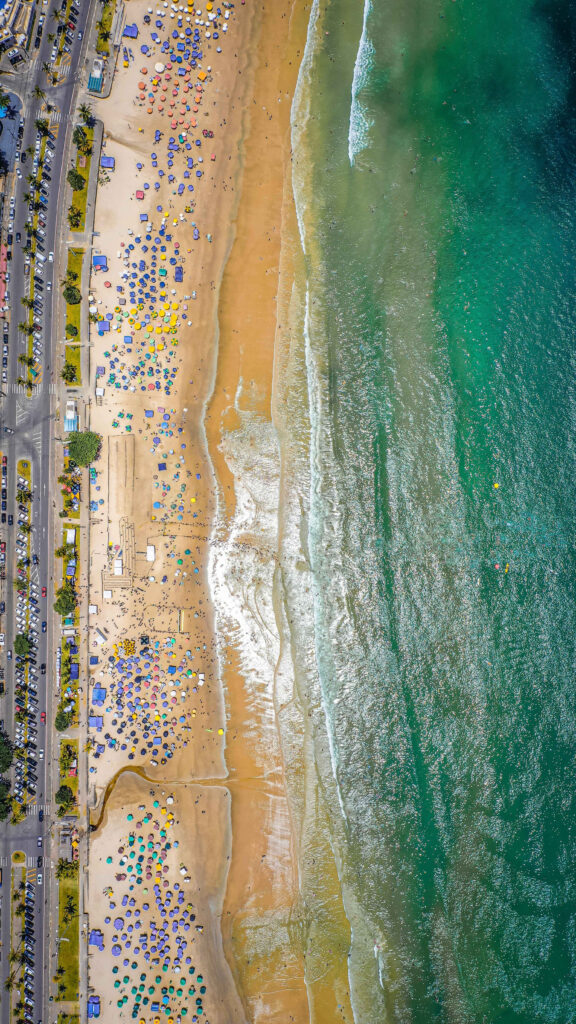 Vibrant Beach Scene with Colorful Umbrellas and Inviting Waters Wallpaper
