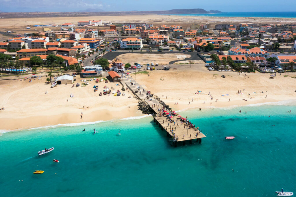 Sunny Beach Wallpaper: Turquoise Waters & Bustling Pier Scene