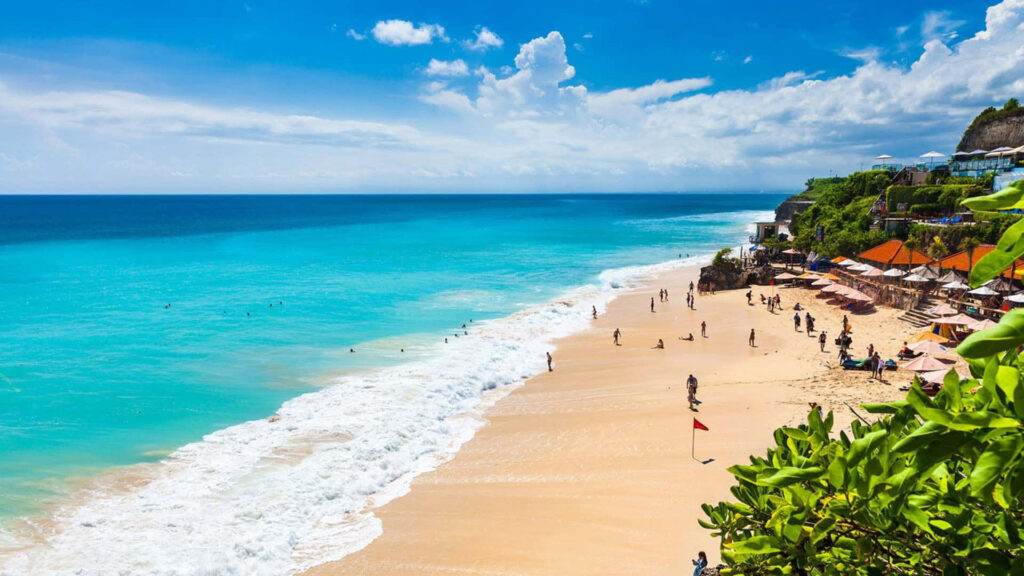 Vibrant Beach Scene: Turquoise Waters, Sandy Shore & Lush Cliffs Wallpaper