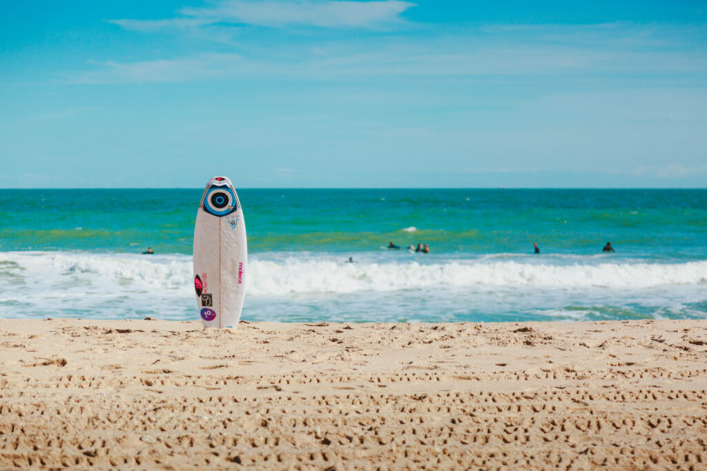 Vibrant Beach Wallpaper: Surfboard in Golden Sand & Turquoise Waves