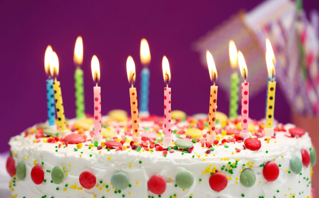 Colorful Birthday Cake with Candles on Purple Background Wallpaper