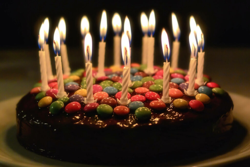 Vibrant Birthday Cake with Colorful Buttons and Flickering Candles Wallpaper