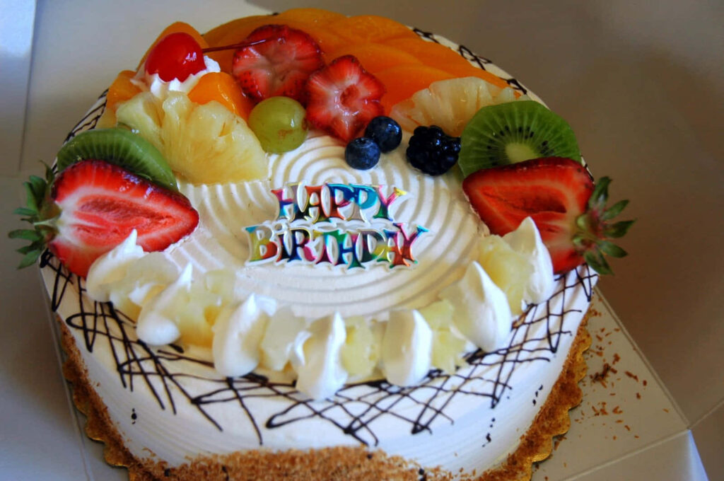 Colorful Birthday Cake with Fresh Fruits and Candles - Festive Delight Wallpaper