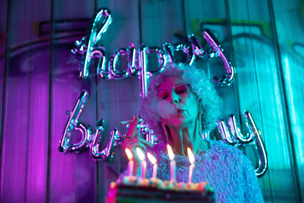 Joyful Elderly Woman Birthday Celebration with Neon Wallpaper