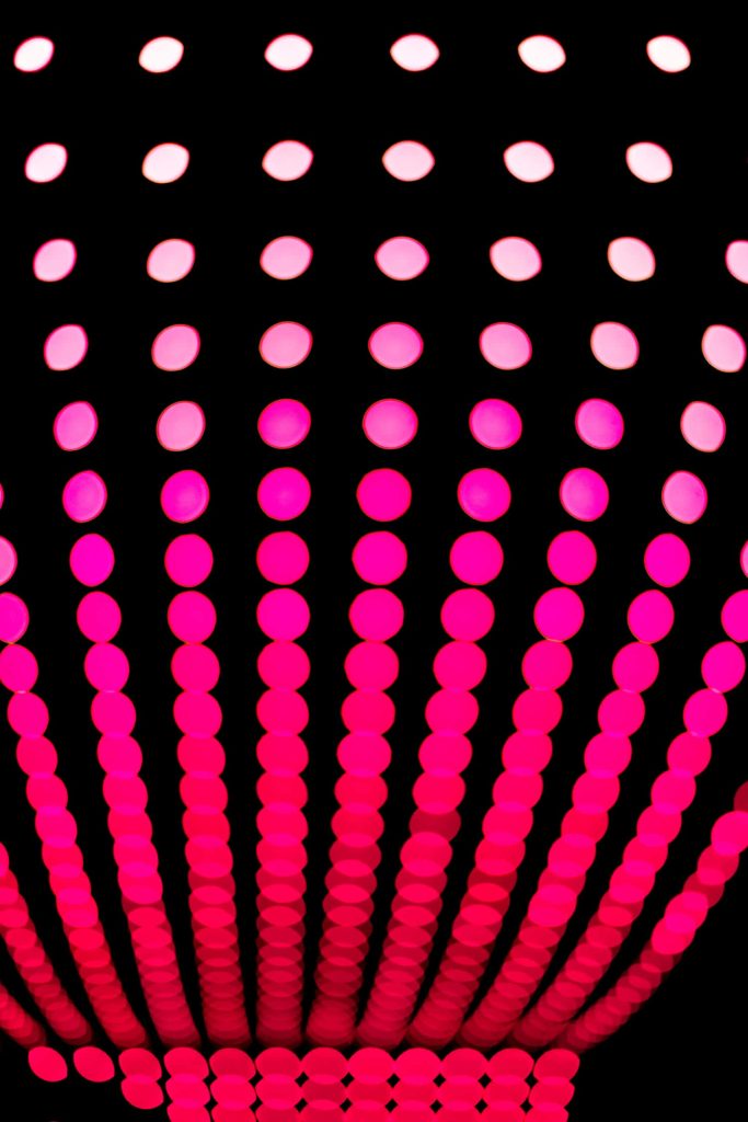 Black and pink abstract wallpaper with vibrant luminous dots in curved vertical rows on black background