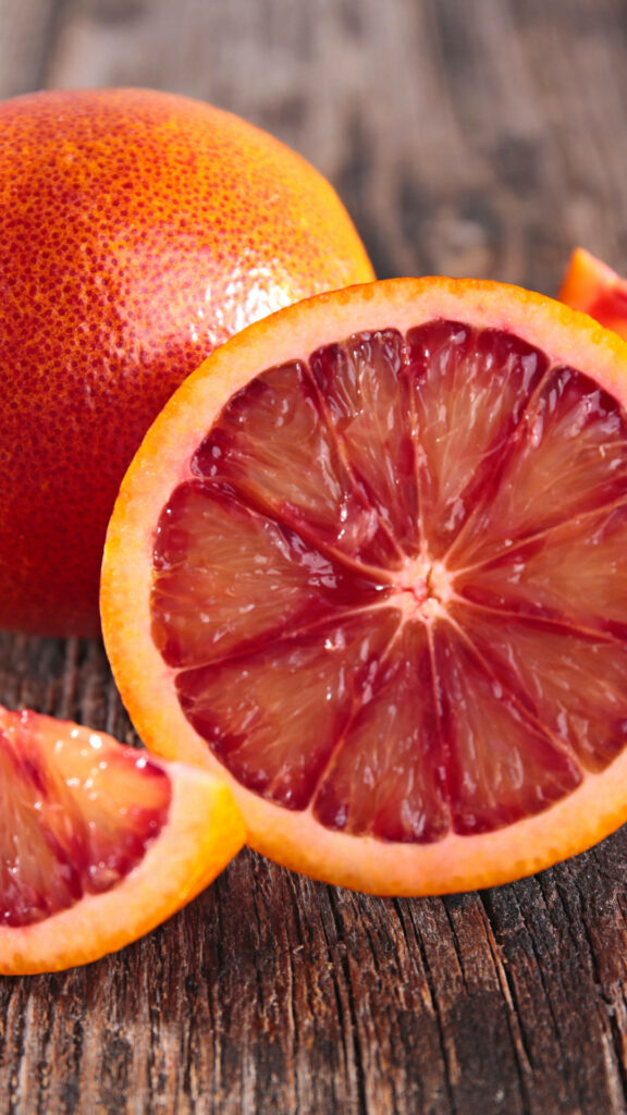 Vibrant blood orange slice with rich red hues and retro style on rustic wooden background Wallpaper
