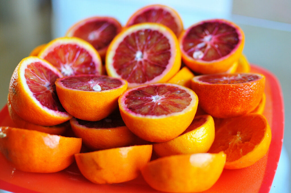 Close-up of fresh sliced blood orange with vibrant red interiors and bright orange rinds wallpaper
