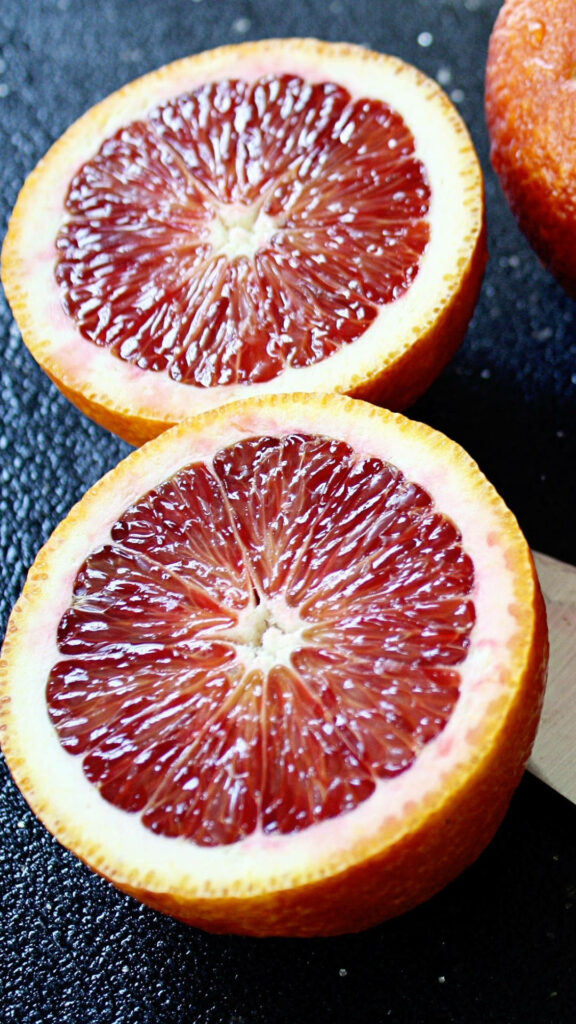 Close up of vibrant juicy blood orange with red and orange hues on wallpaper background