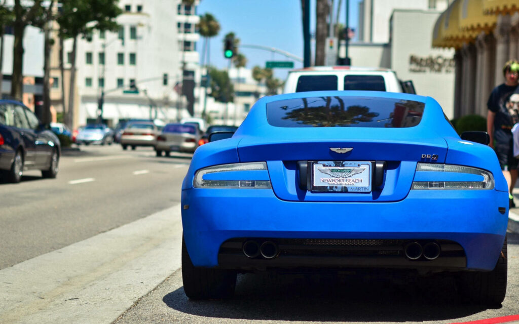 Vibrant Blue Aston Martin DB9 Wallpaper: Luxurious Urban Scene