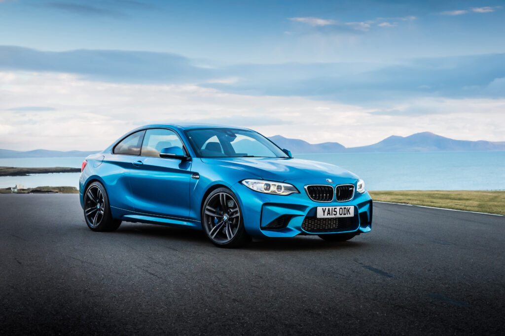 Vibrant Blue BMW M2 F87 Side View: Scenic Open Roads & Mountains Wallpaper