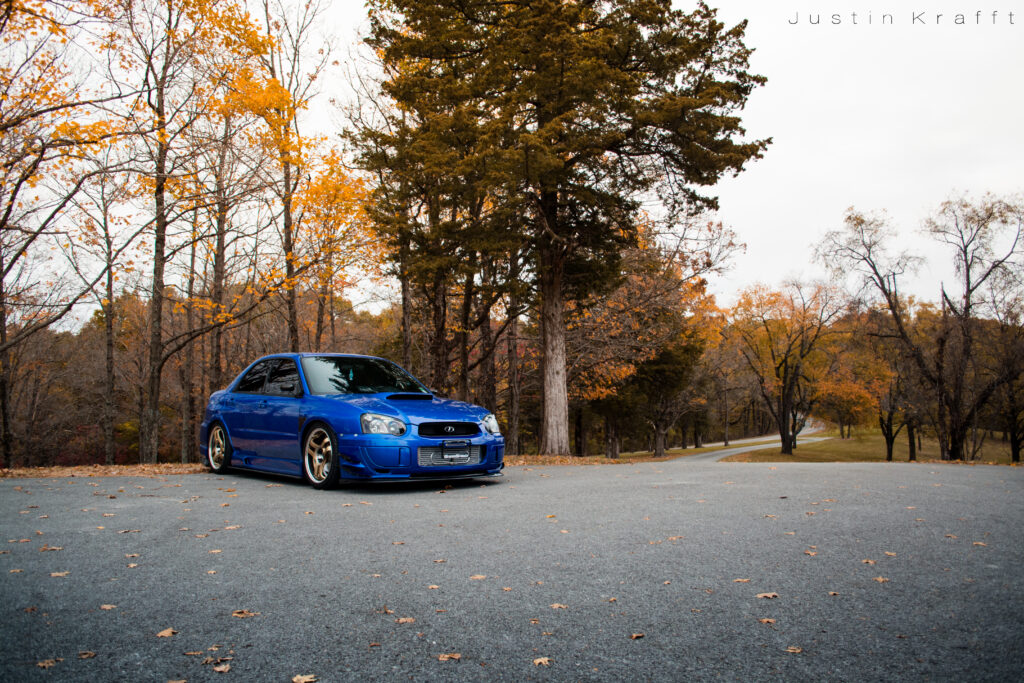 Blue Car on Tree-Lined Path: Autumn Landscape Wallpaper