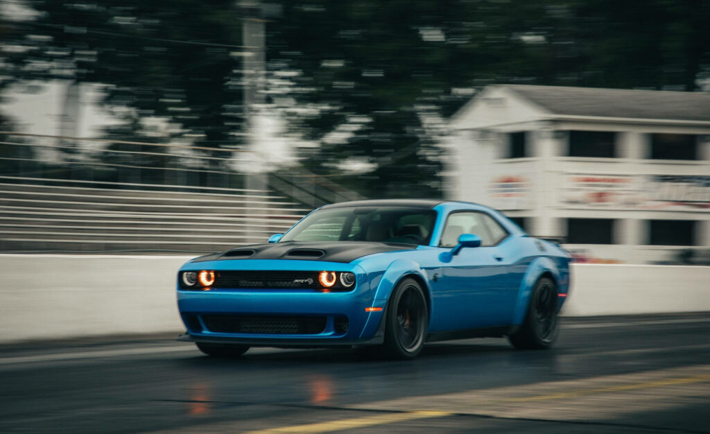 Vibrant blue Dodge Challenger speeding on track showcasing powerful American muscle car motion Wallpaper