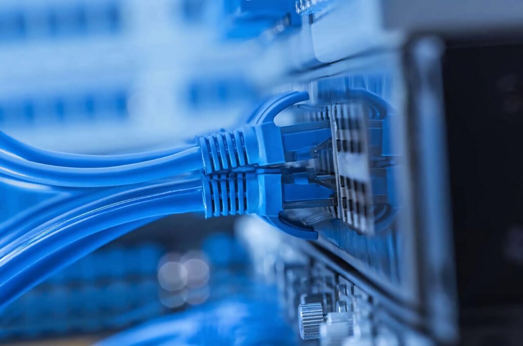 Close-up of vibrant blue Ethernet cables connected to a network switch in a modern tech setting Wallpaper