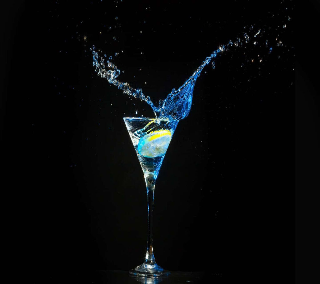 Vibrant blue martini splash in clear glass on dramatic black background dynamic wallpaper