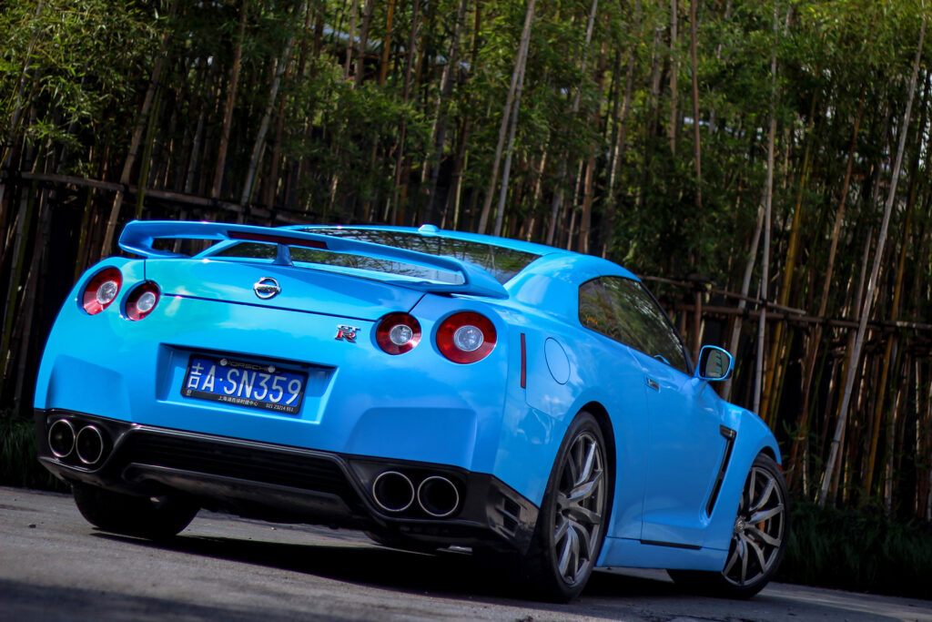 Vibrant Blue Nissan GTR R35 Rear View Wallpaper with Greenery