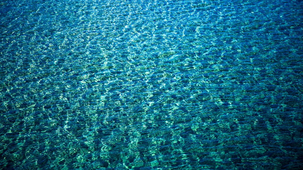 Vivid clear blue water wallpaper with intricate ripples gentle waves calming sea patterns background