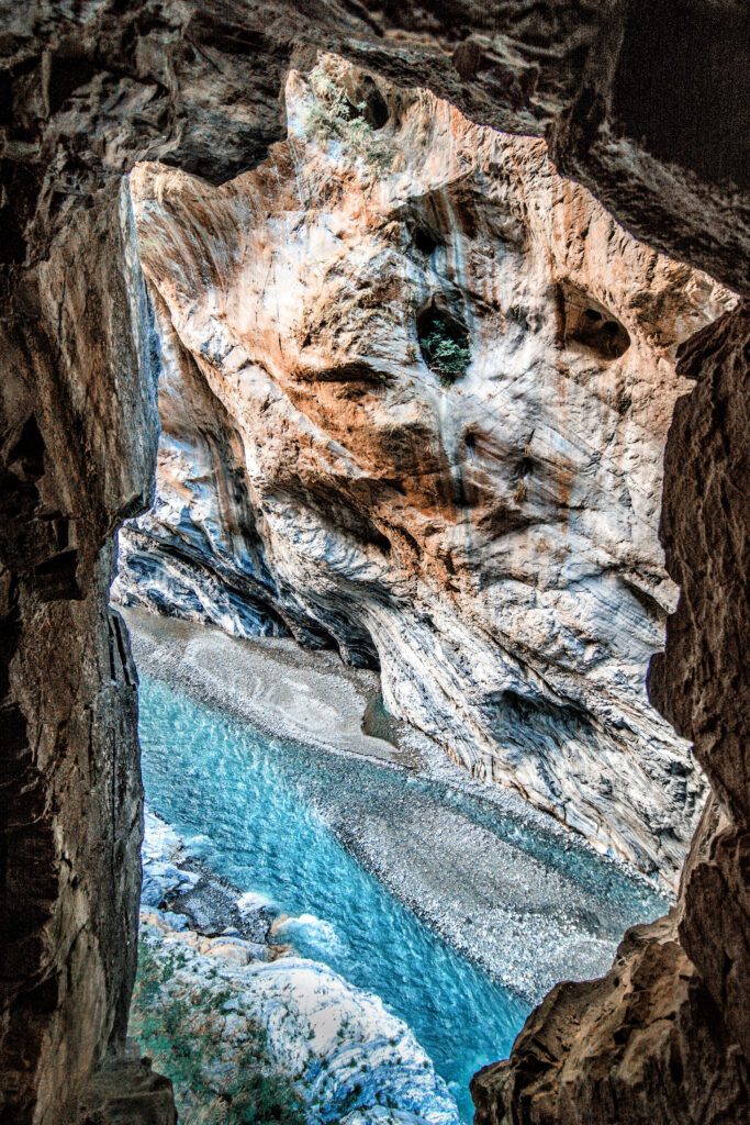 Top view vibrant blue river flowing between rugged textured rock formations natural landscape wallpaper