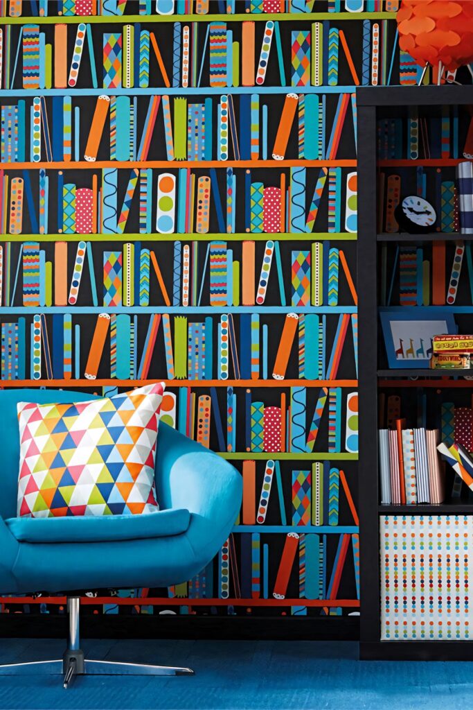 Vibrant bookshelf wallpaper with colorful geometric patterns beside bold blue chair and pillow