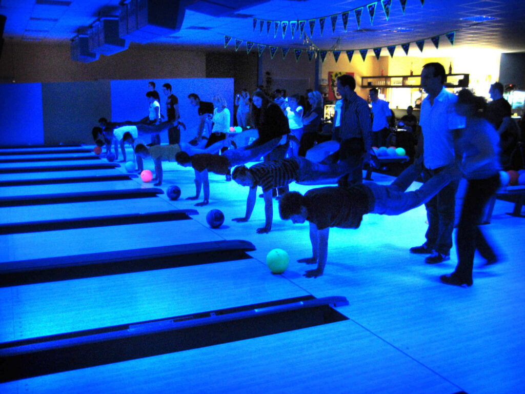 Vibrant bowling alley scene with lively crowd colorful balls and glowing blue lights wallpaper