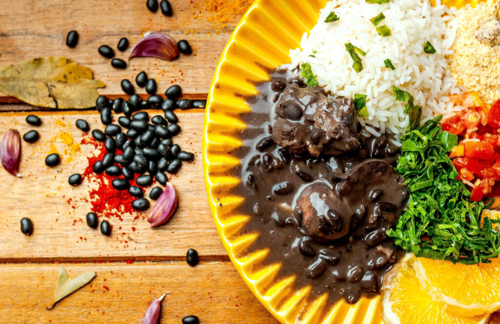 Colorful Brazilian Feijoada on Yellow Plate: Vibrant Culinary Delight Wallpaper