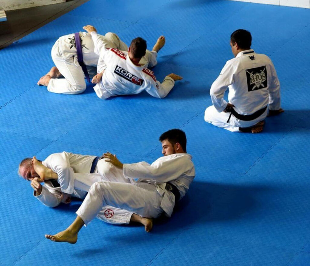Vibrant Brazilian Jiu-Jitsu Wallpaper: Training Session on Blue Mat