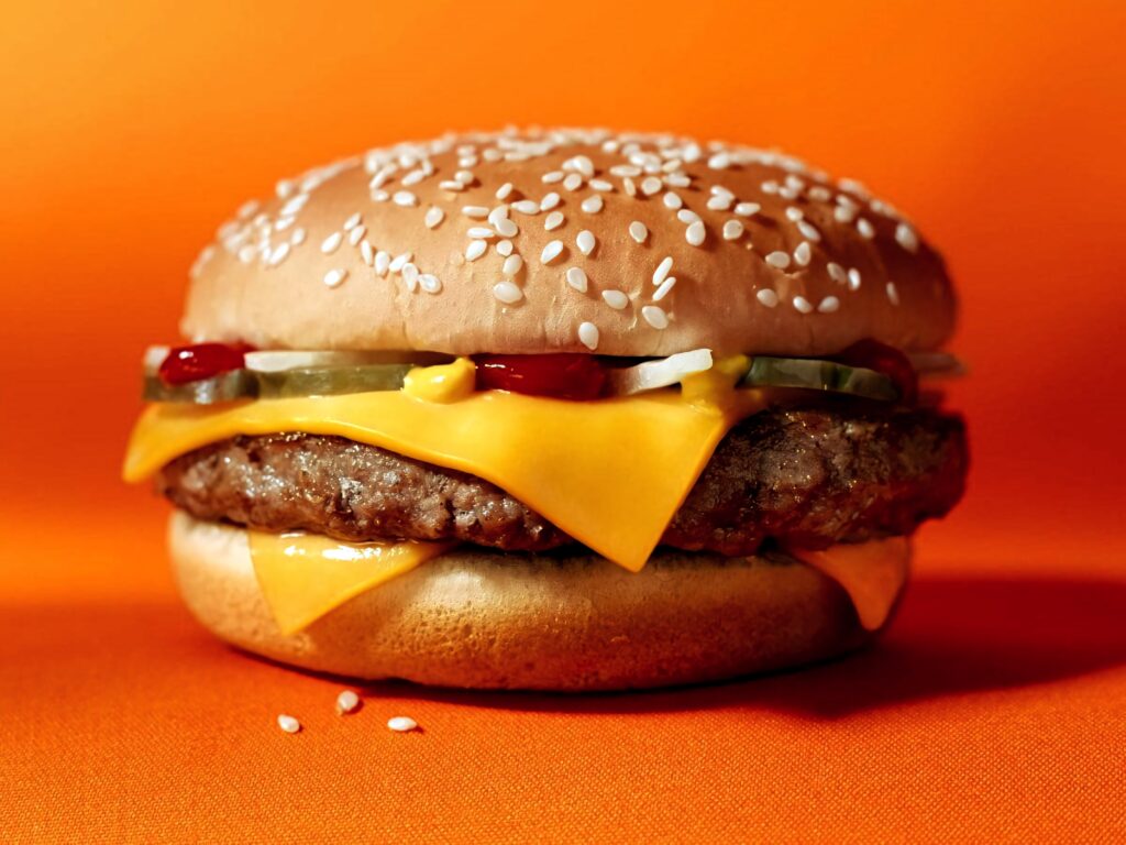 Burger King cheeseburger with juicy beef patty melted cheddar cheese pickles onions on sesame bun Wallpaper