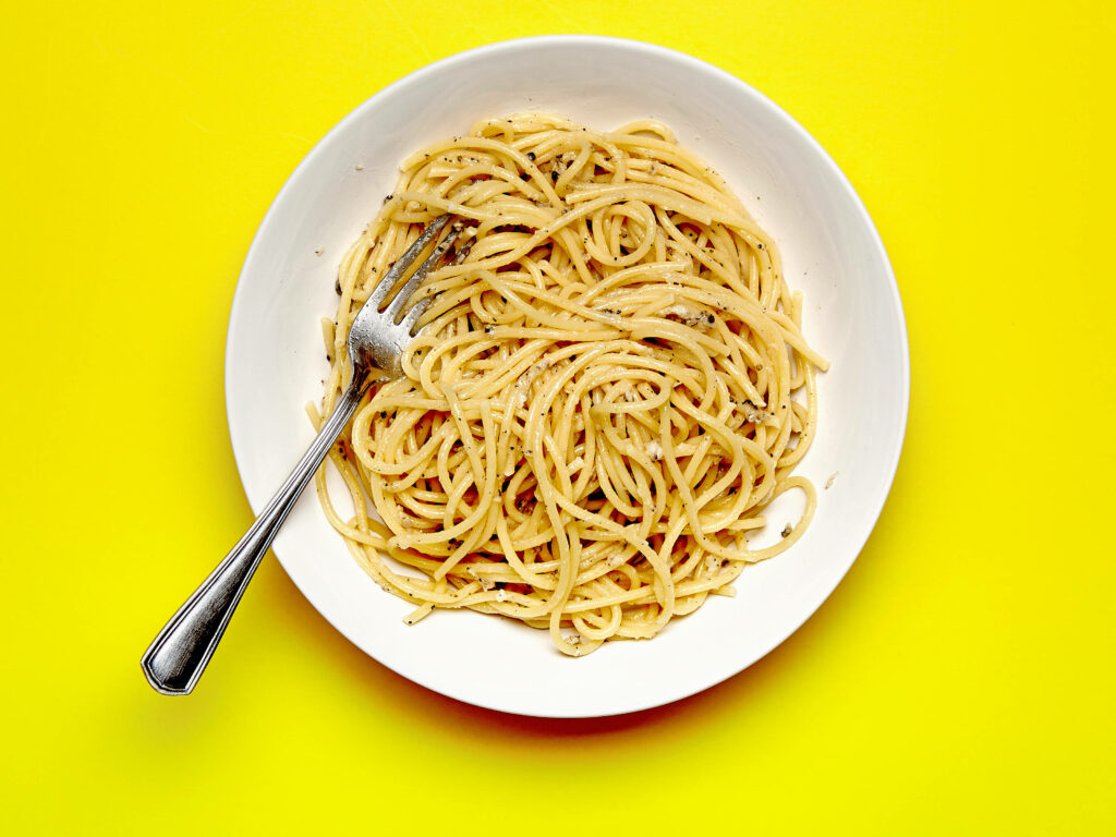 Vibrant Cacio e Pepe Wallpaper: Delicious Pasta on Yellow Surface