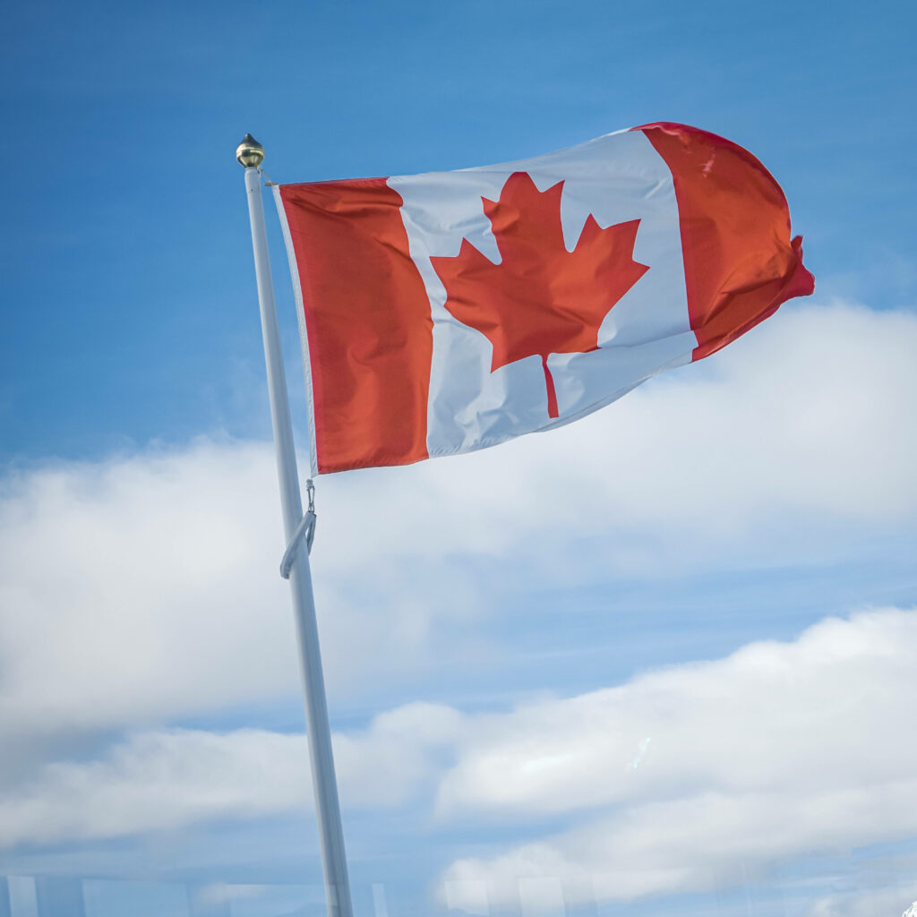 Canadian flag waving bright blue sky fluffy white clouds patriotic high resolution wallpaper background