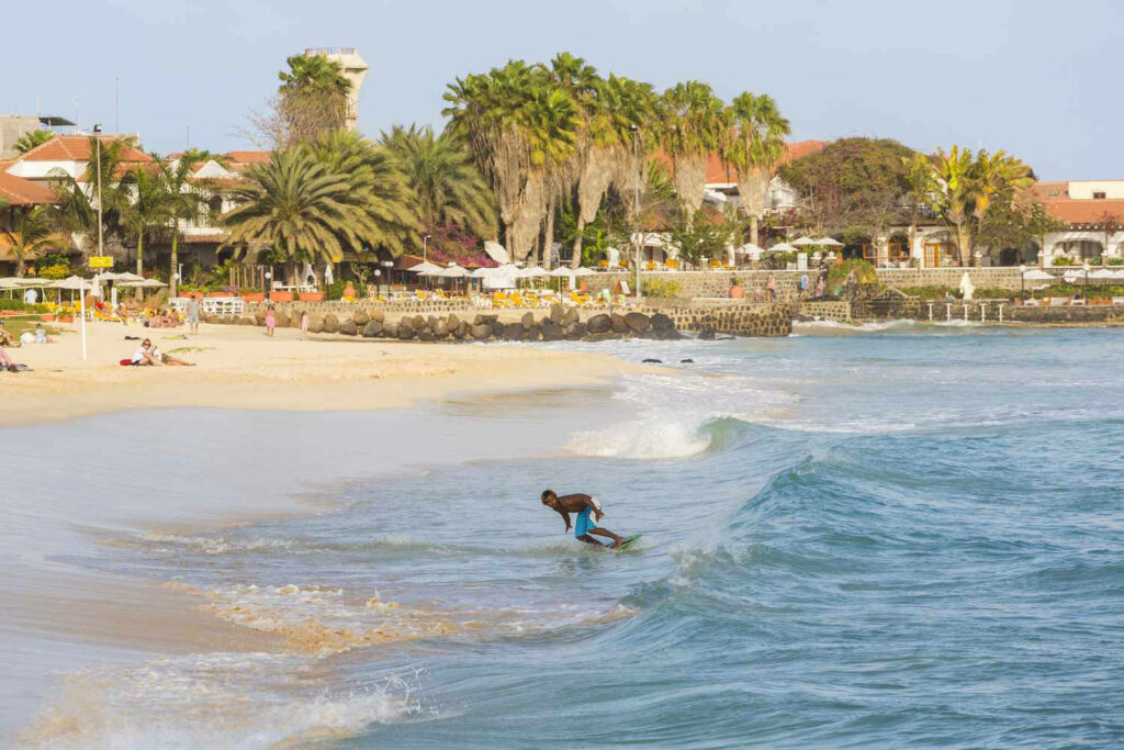 Surfer Riding Waves Amid Cape Verde's Lush Beachfront Paradise Wallpaper