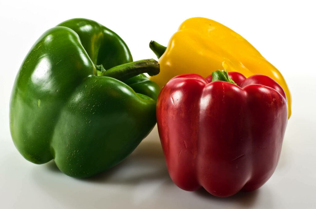 Vibrant Capsicum Wallpaper: Glossy Green, Red & Yellow on White Background