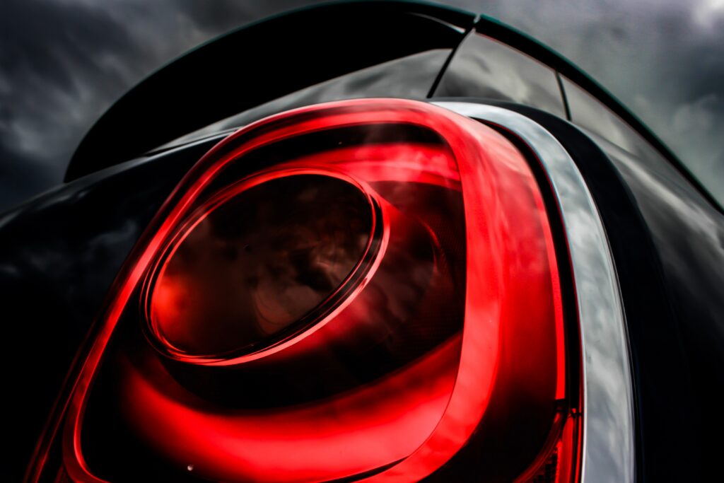 Vibrant Red Car Taillight Close-Up Against Moody Sky Wallpaper