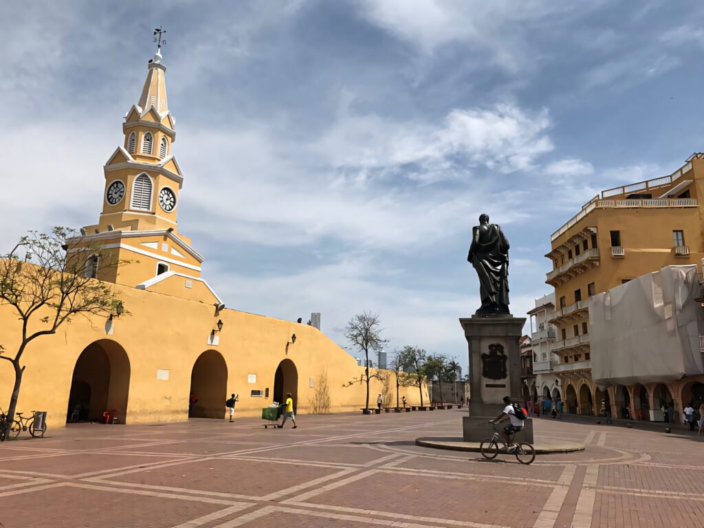Vibrant Cartagena Clock Tower and statue with colonial buildings in lively Colombian square wallpaper