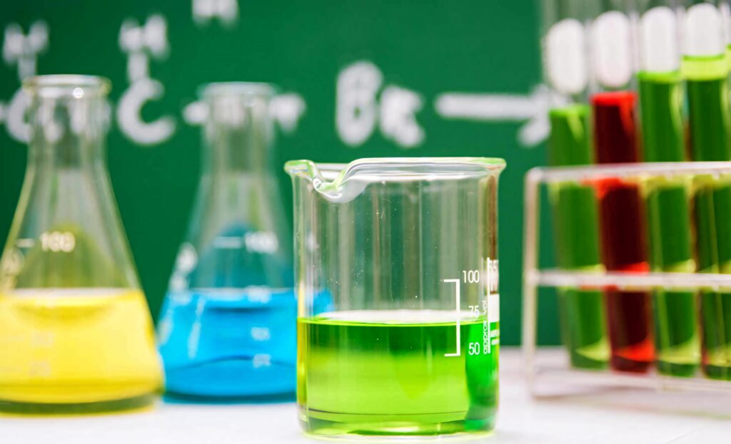 Vibrant chemistry lab wallpaper with colorful beakers and test tubes on chalkboard formulas background