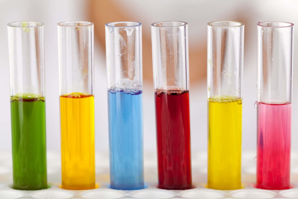 Six colorful test tubes in a white rack with vibrant chemistry liquids on bright background Wallpaper