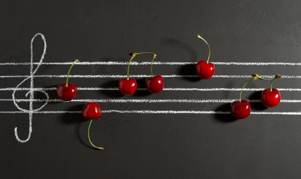 Vibrant Cherry Wallpaper: Musical Notes on Black Background