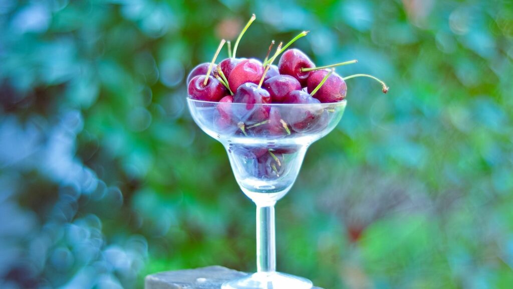 Vibrant Cherry Wallpaper: Refreshing Glass & Soft Green Background