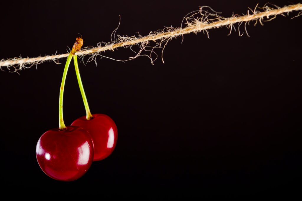 Vibrant Cherry Wallpaper: Shiny Red Cherries on Dark Rustic Background