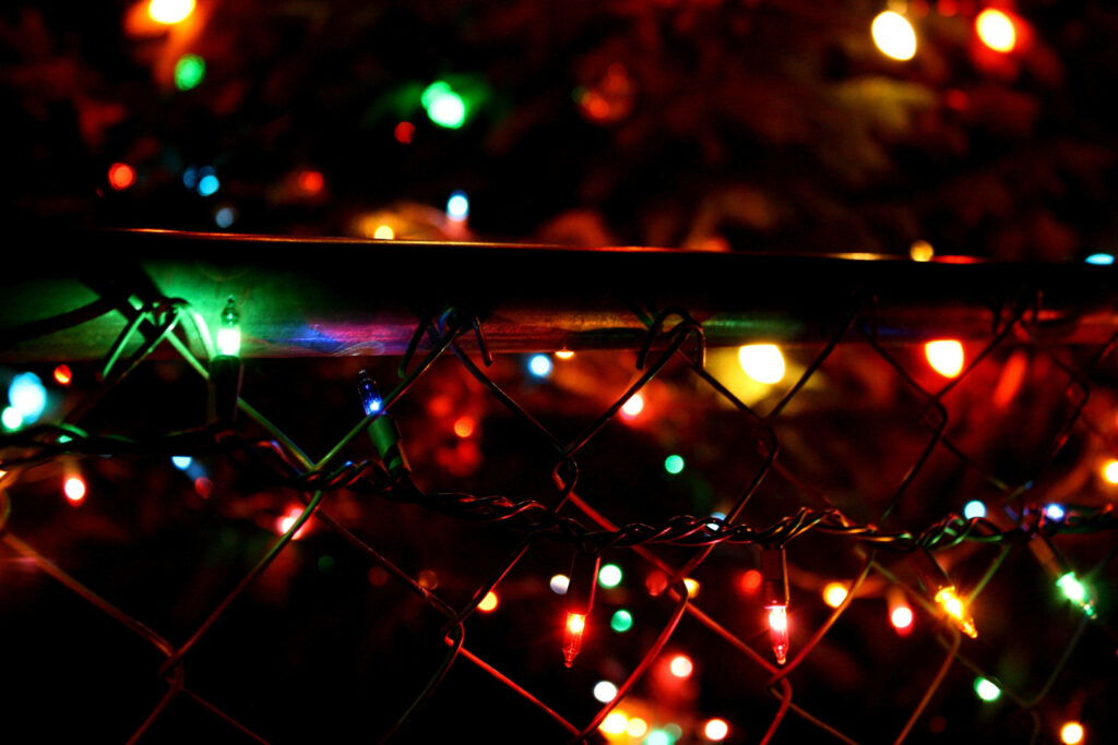 Festive Christmas Lights on Fence: Enchanting Holiday Background Wallpaper