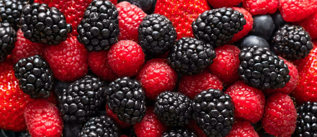 Close-up vibrant wallpaper of ripe boysenberries strawberries and raspberries with rich textures