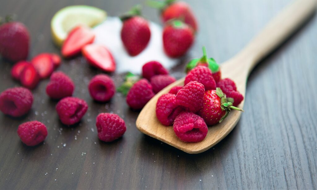 Close-Up of Ripe Raspberries & Strawberries on Wooden Spoon Wallpaper